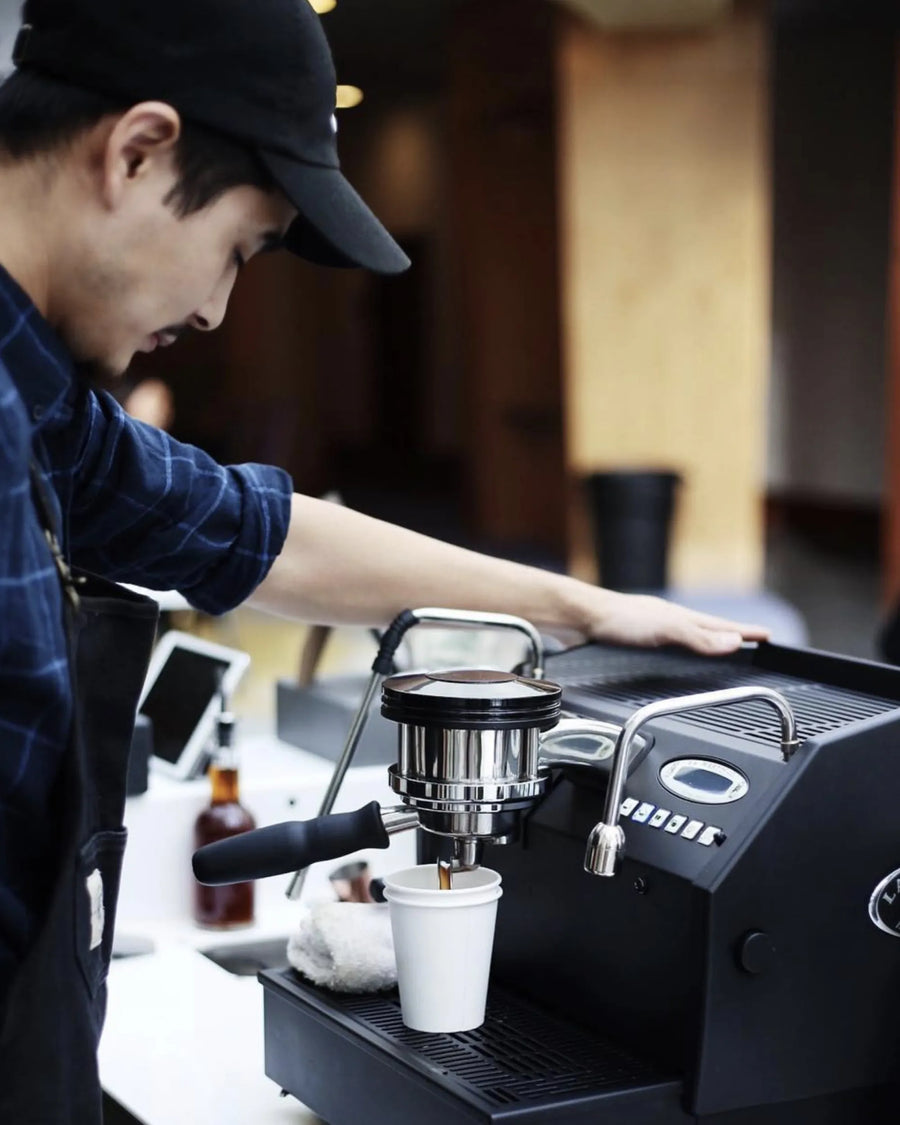 Gentleman wearing a hat making a cup of coffee with an espresso machine